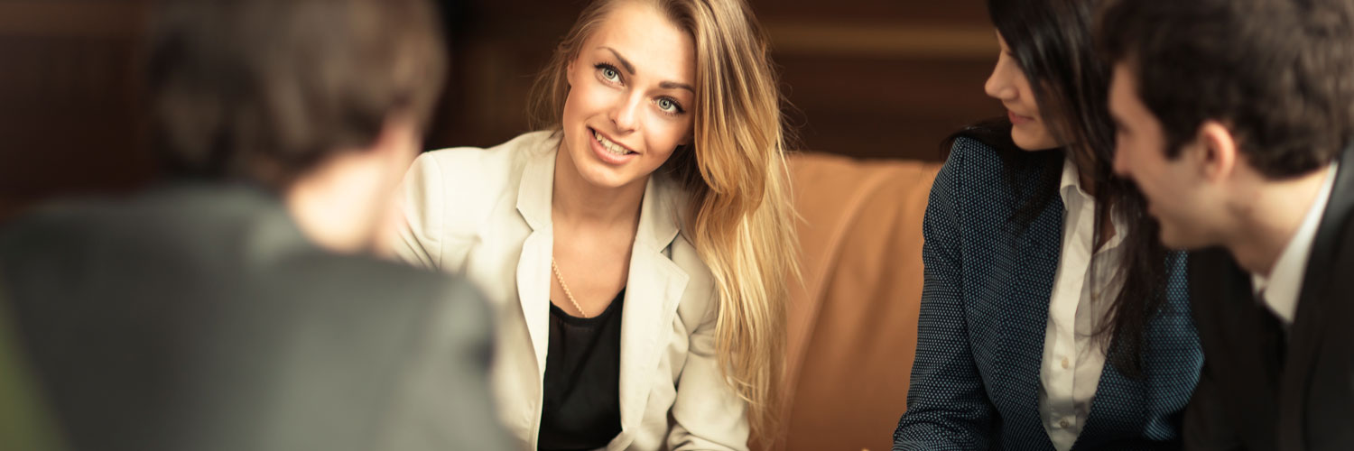 Professional woman in suit with long blonde hair having a meeting with coworkers