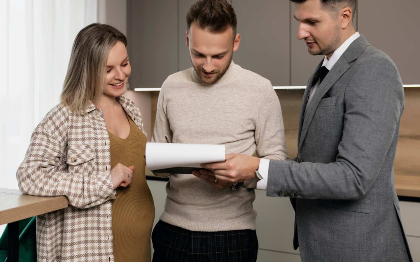 three people standing and reviewing a document